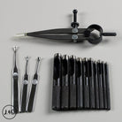 Set of black leather tools including wing dividers and hole punches on a gray background.