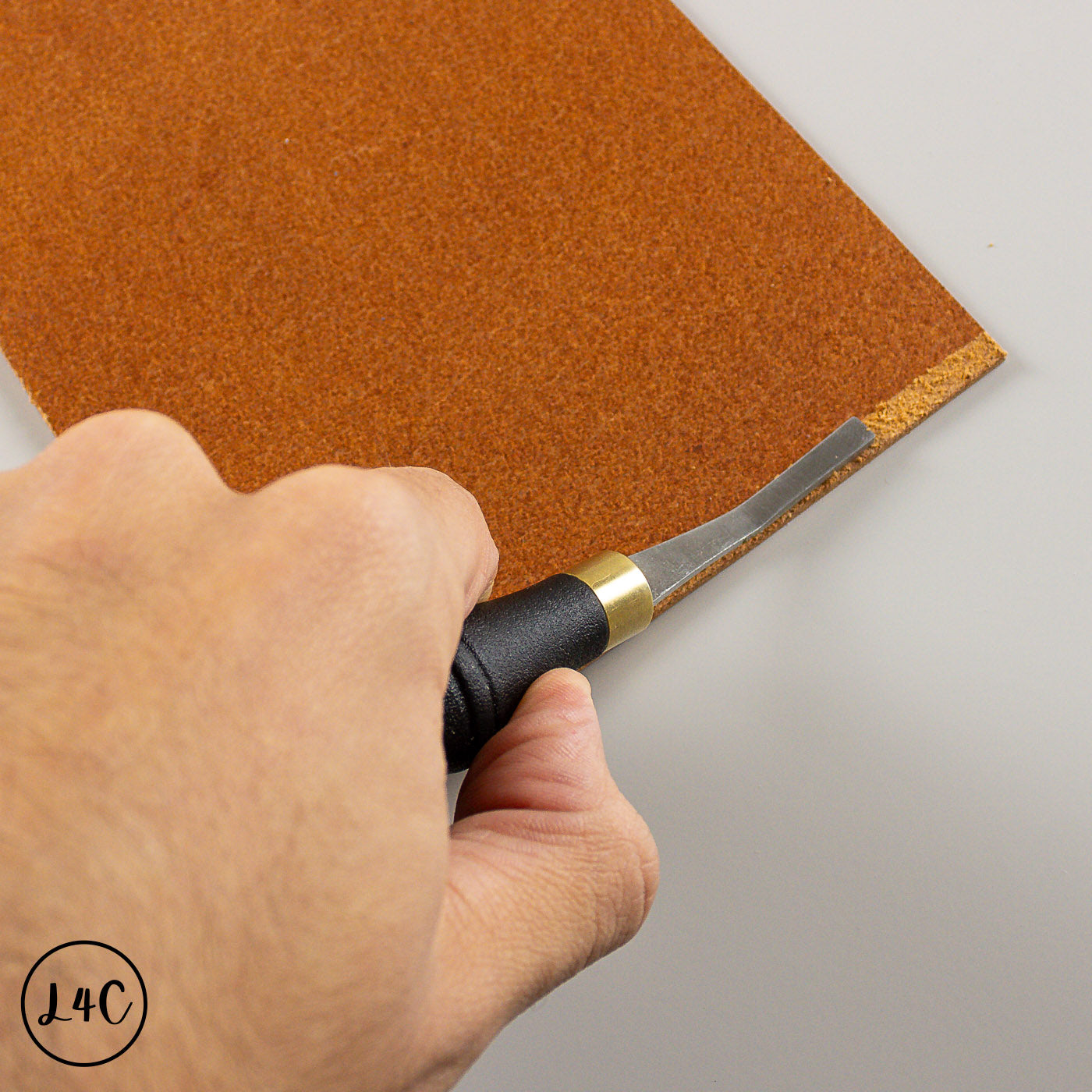 Hand using a rougher on a piece of brown leather.