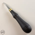 Black leather rougher with gold ferrule on a light beige background
