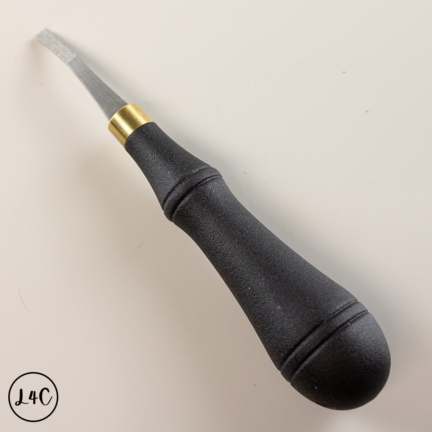 Black leather rougher with gold ferrule on a light beige background