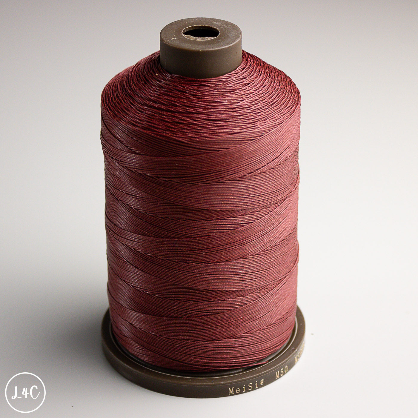 Spool of MeiSi Waxed Linen Thread on a gray background
