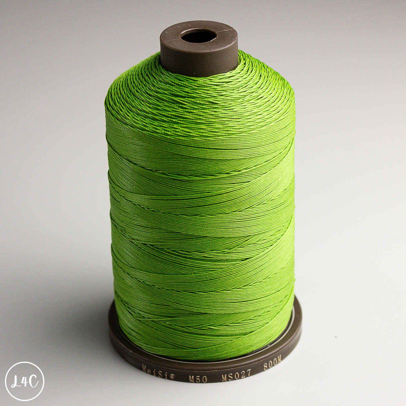 Spool of green MeiSi Waxed Linen Thread on a gray background