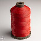 Spool of red MeiSi Waxed Linen Thread on a gray background