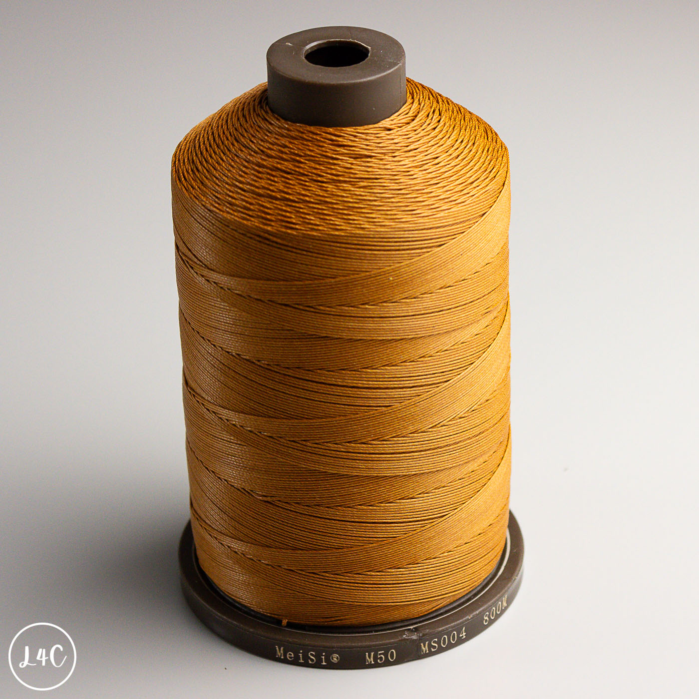 Spool of brown MeiSi Waxed Linen Thread on a gray background