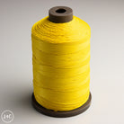 Spool of yellow MeiSi Waxed Linen Thread on a gray background