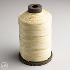 Spool of beige thread on a gray background
