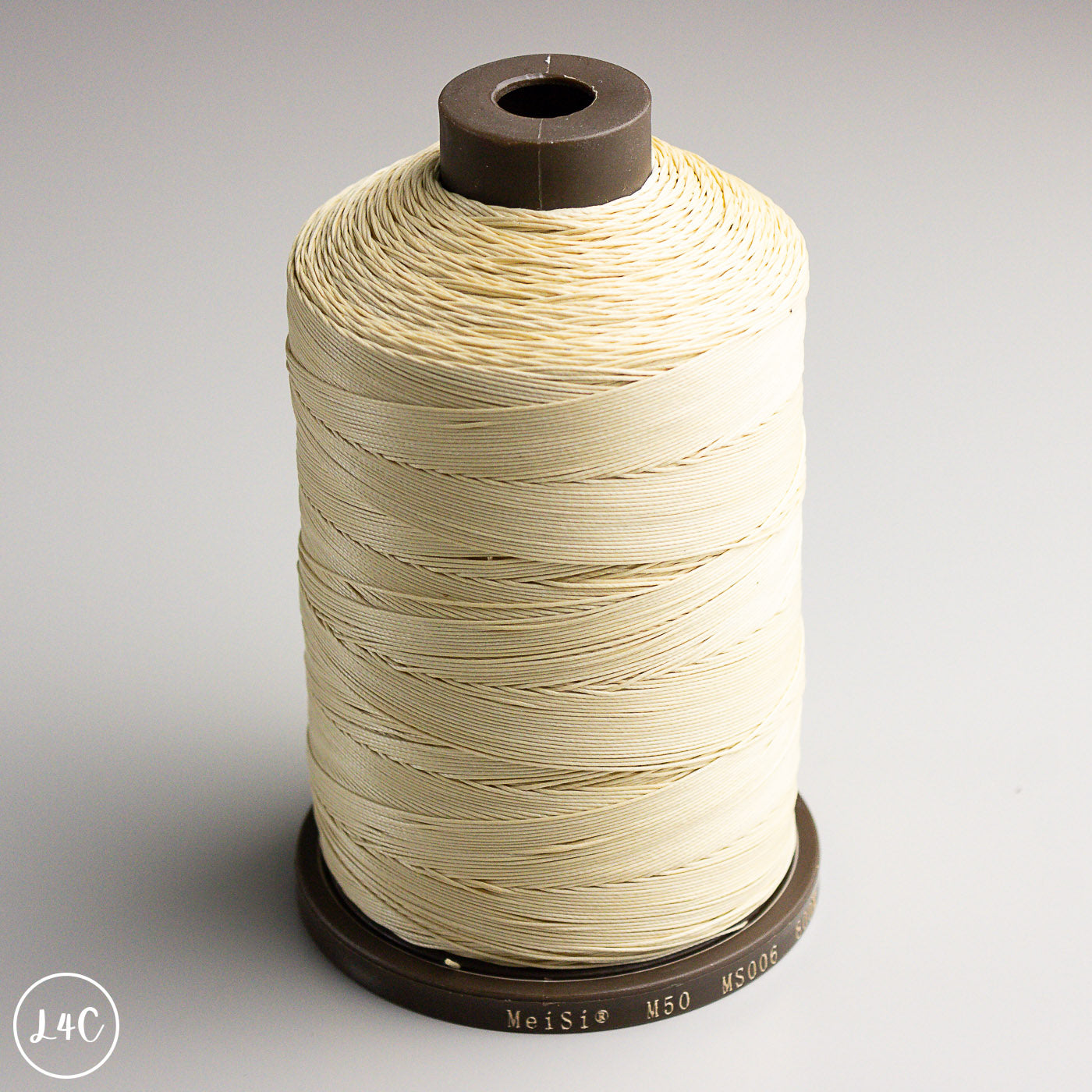 Spool of beige thread on a gray background