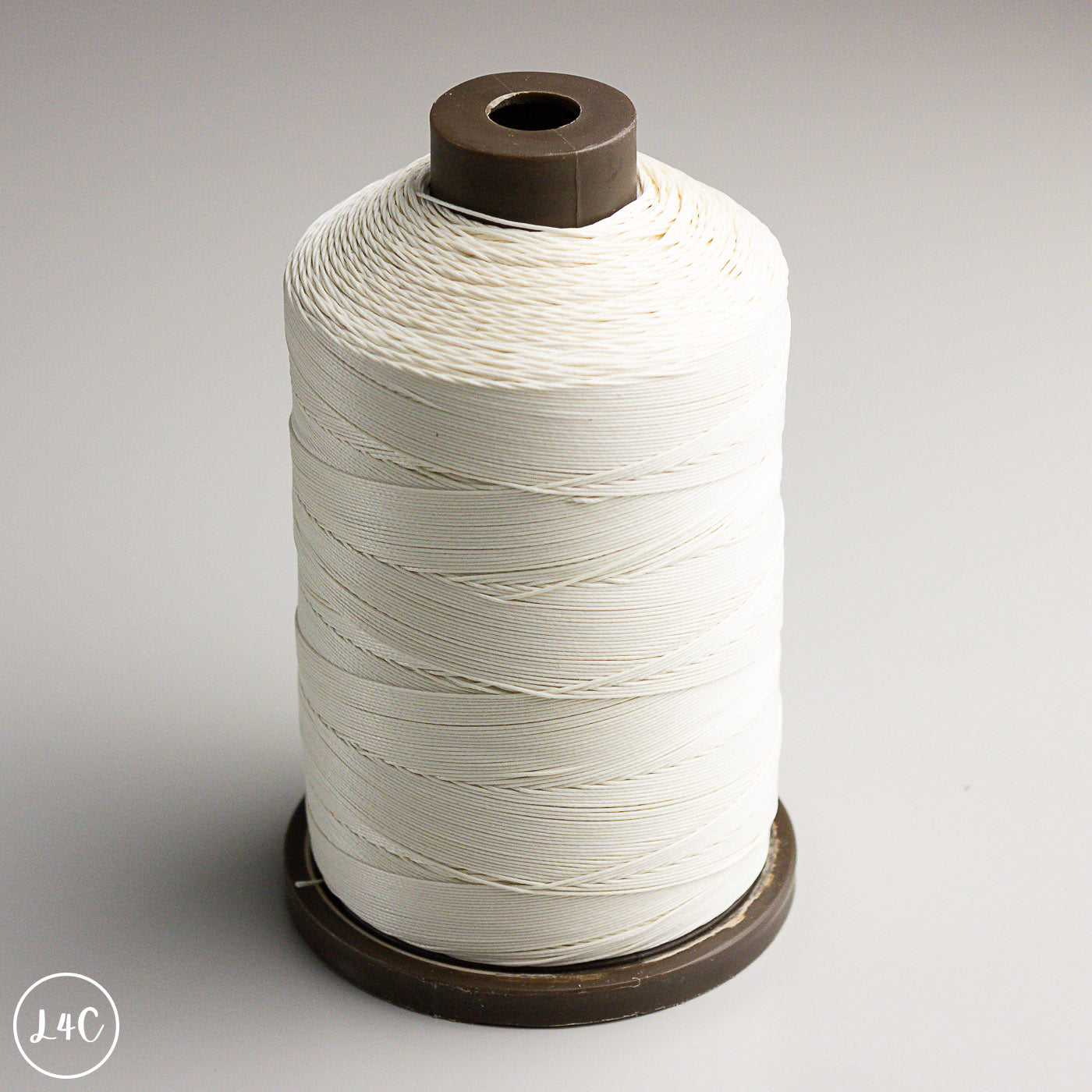 Spool of white thread on a gray background