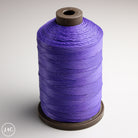 Spool of purple thread on a gray background