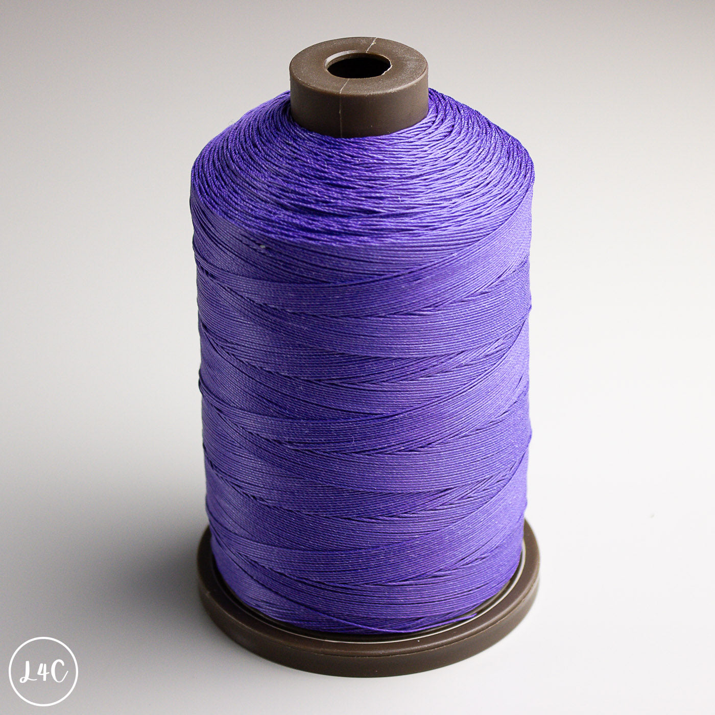 Spool of purple thread on a gray background