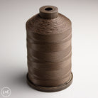 Spool of brown thread on a white background