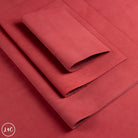 A stack of folded red nubuck leather material on a matching red background.