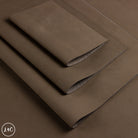 A stack of folded brown  leather sheets, displayed diagonally on a matching brown background. 