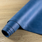 Rolled-up blue leather sheet on a wooden surface