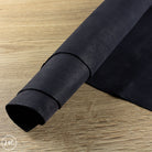 Roll of black leather on a wooden surface