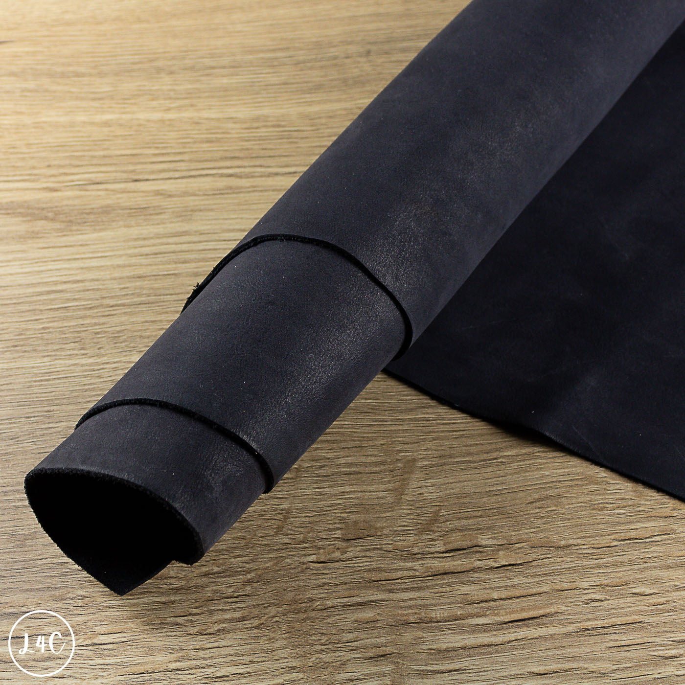 Roll of black leather on a wooden surface