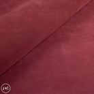 Close-up of maroon fabric with a visible brand logo in the corner.