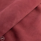 Close-up of red-brown suede with a visible brand logo in the corner.