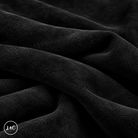 A close-up of draped black suede leather with a soft, plush texture, showing deep folds and shadows. 
