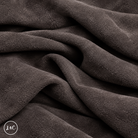 A close-up of draped dark suede leather with a soft, plush texture, showing deep folds and shadows. 