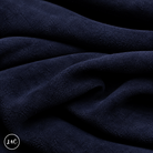 A close-up of draped navy suede leather with a soft, plush texture, showing deep folds and shadows. 