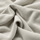 A close-up of draped white suede leather with a soft, plush texture, showing deep folds and shadows. 