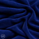 A close-up of draped blue navy suede leather with a soft, plush texture, showing deep folds and shadows. 