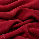 A close-up of draped red suede leather with a soft, plush texture, showing deep folds and shadows. 