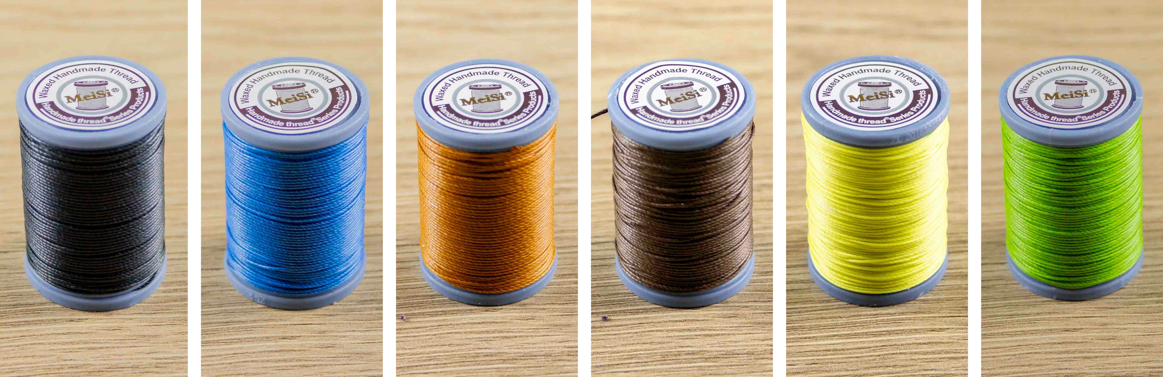Six spools of thread in different colors on a wooden surface