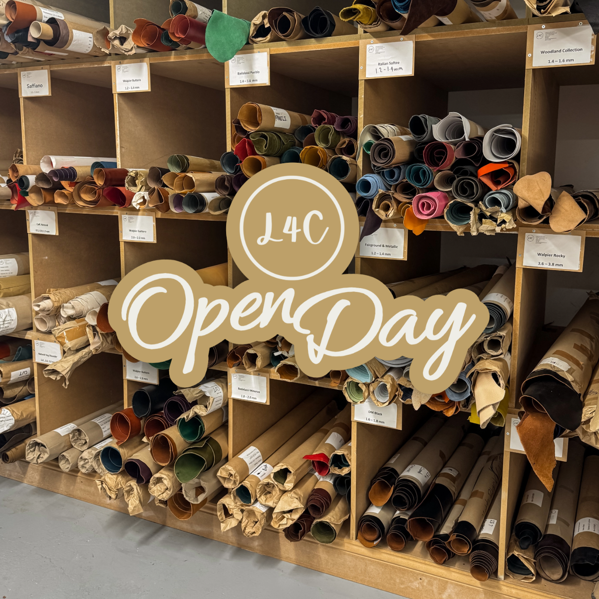 A wooden display shelf filled with rolled fabric or material samples in many colors, with a large overlaid badge reading 'L4C OpenDay'. 