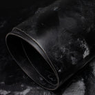 Roll of black bridle leather on a textured dark background