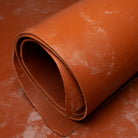 Rolled-up piece of brown leather on a textured surface