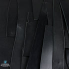 Close-up of black leather off cuts with a brand logo in the corner.