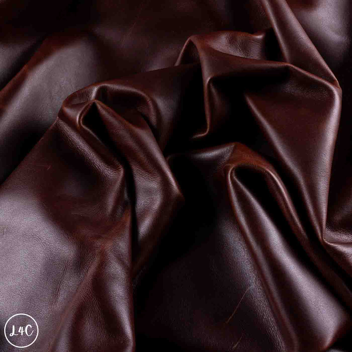 Dark brown leather fabric draped in soft folds, showing a smooth texture and rich color.