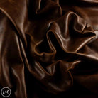 Dark brown draped leather with a smooth, glossy texture and soft folds