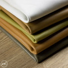Stack of smooth leather packs in various colors on a wooden surface