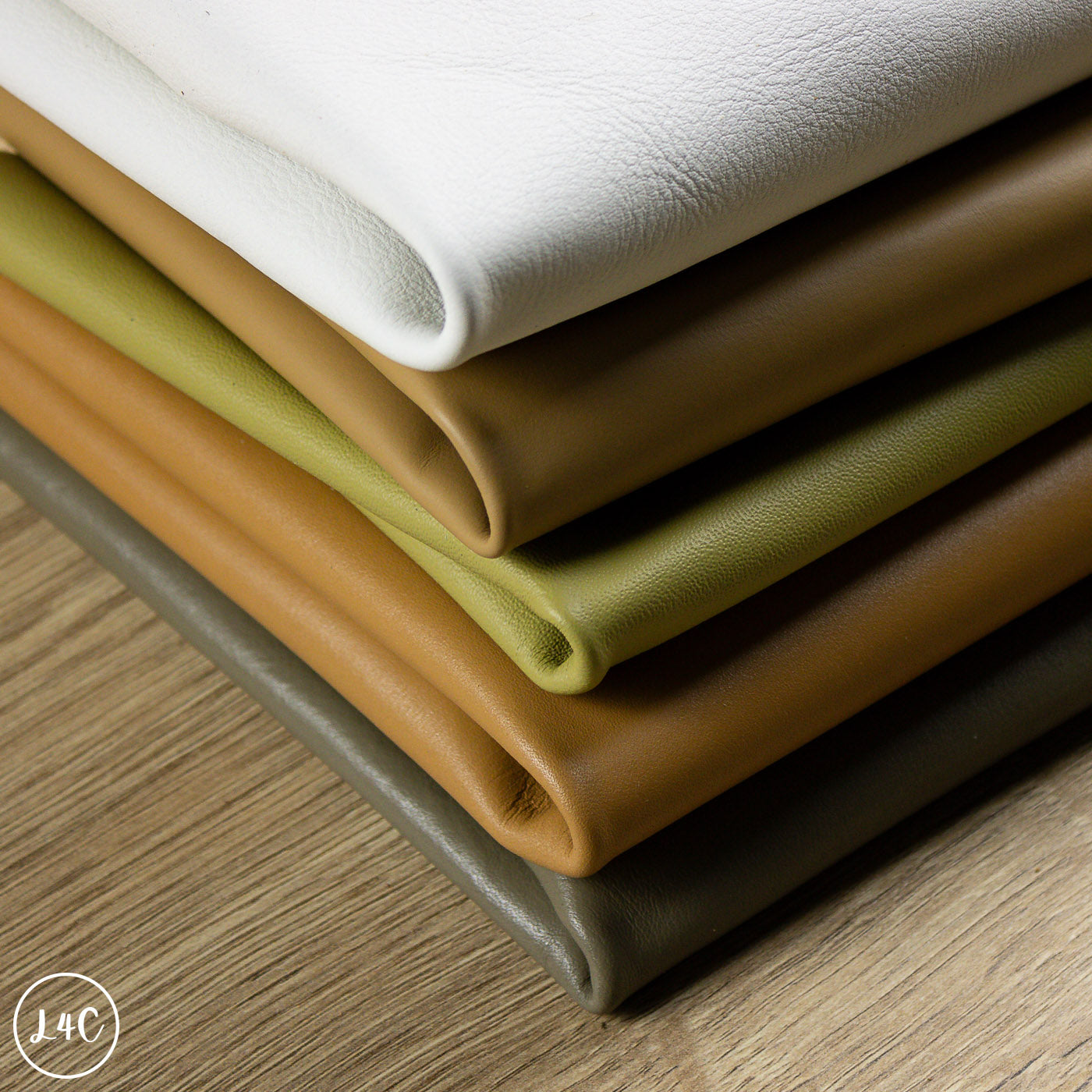 Stack of smooth leather packs in various colors on a wooden surface