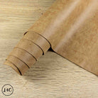 A roll of tan textured leather laid diagonally across a light wood surface.