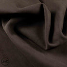 A close-up of draped dark brown fabric with soft folds and a subtle matte texture.