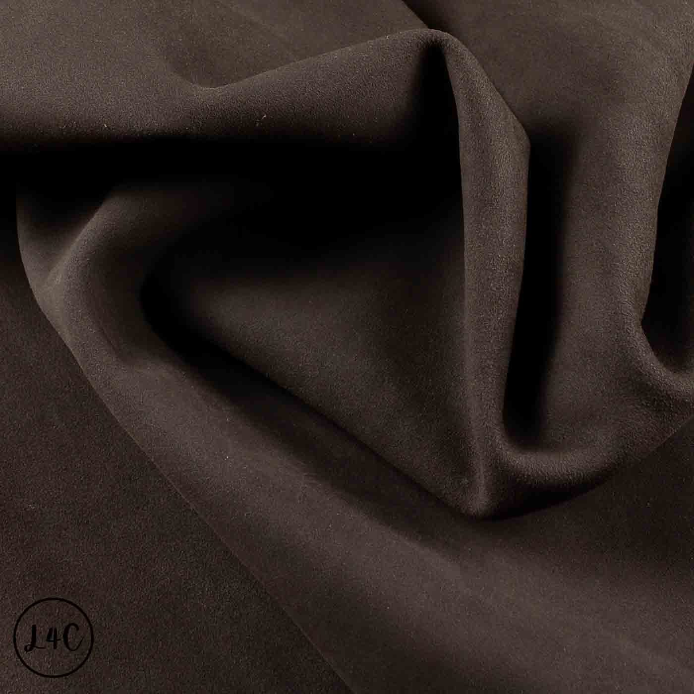 A close-up of draped dark brown fabric with soft folds and a subtle matte texture.