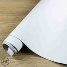 A roll of white textured leather hide, partially unrolled on a light brown wooden surface. 